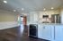 Modern open-concept kitchen with sleek white cabinetry, stainless steel appliances, and hardwood floors, leading to a bright living area.