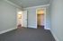 Spacious bedroom with soft gray walls, plush carpet, and access to a bright bathroom and walk-in closet.