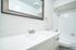 Modern and bright bathroom with sleek white fixtures, elegant countertop, and stylish mirror.