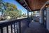 Charming balcony with a rustic wooden ceiling, offering a scenic view of lush green trees and a quiet neighborhood street.