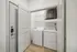 Modern apartment laundry nook with washer and dryer tucked behind elegant doors, boasting functional shelving and contemporary design.