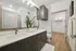 Elegant bathroom with dual sinks, sleek cabinetry, and modern fixtures, leading to a spacious walk-in closet.