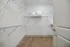 Spacious walk-in closet with modern shelving and sleek wooden flooring, perfect for maximizing storage and organization.