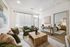 Elegant modern living room with plush green armchairs, cozy sofa, and rustic wooden accents, flowing into a serene bedroom.