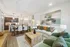 Elegant open-concept living room with stylish decor, cozy seating, and modern kitchen in background.