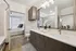 Elegant bathroom showcasing a modern double vanity with chic lighting fixtures, leading to a cozy bedroom with natural light.
