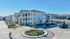 Modern apartment complex featuring stylish three-story buildings with balconies, set in a beautifully landscaped green area and ample parking.