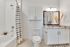 Modern bathroom featuring an elegant granite countertop, stylish mirror with lighting, and a sleek shower-tub combination with a chic striped curtain.