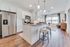Contemporary open kitchen with sleek stainless steel appliances, elegant wooden floors, and a cozy seating area, bathed in natural light.