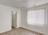 Bright bedroom with soft carpet flooring and large window with vertical blinds, offering a cozy and inviting atmosphere.