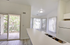 Bright kitchen with modern appliances, large windows, and sliding doors to a charming balcony with a scenic view.