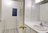 Bright utility room featuring a convenient washer and dryer setup adjacent to a sleek bathroom with stylish sink and large mirror.