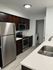 Sleek modern kitchen with stainless steel appliances, dark wood cabinets, and pristine countertops. Includes a convenient in-unit washer and dryer.