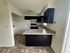 Chic apartment kitchen with sleek dark cabinets, modern appliances, and a stunning marble countertop.