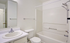 Bright and contemporary bathroom featuring a sleek white vanity, modern fixtures, and a pristine bathtub.