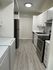 Modern kitchen with sleek appliances, ample cabinetry, and elegant light wood flooring.