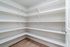 Spacious walk-in pantry with sleek white shelves and modern design.