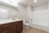 Modern bathroom with sleek wooden vanity, pristine white fixtures, and bright ambient lighting for a spa-like experience.