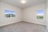 Bright and inviting room with neutral walls and carpet, featuring large windows offering scenic views and natural light.