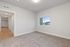 Bright and modern room with plush carpet, large window for natural light, and sleek hallway access, perfect for a stylish living space.