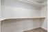 Spacious walk-in closet with dual hanging rods and ample shelving, perfect for organized storage.