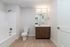 Modern bathroom with sleek wooden vanity, stylish lighting, and elegant bathtub in a serene setting.