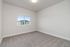 Bright, spacious bedroom with plush carpeting and a large window offering views of the modern apartment complex.