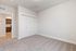 Bright and spacious room with plush carpeting, featuring a modern kitchen view and elegant double-door closet.