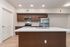 Modern kitchen featuring sleek wooden cabinets, stainless steel appliances, and a stylish island with under-counter sink and bright lighting.