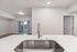 Modern open-plan kitchen with sleek countertop and elegant faucet, leading to a bright living space with balcony view.