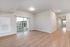 Elegant apartment interior with bright natural light, showcasing chic hardwood floors and a spacious open layout extending to a balcony.
