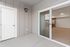 Inviting modern balcony entrance with sliding glass doors opening to a spacious, light-filled interior featuring sleek wooden floors.