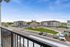 Inviting apartment complex with modern architecture, ample parking, and a sunny courtyard view from the balcony.