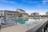 Luxurious apartment community featuring a pristine swimming pool surrounded by stylish lounge chairs and modern architecture under a clear blue sky.