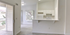 Bright open-concept kitchen with sleek white cabinetry, adjacent to a sunlit living area and balcony access.
