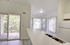 Bright and airy kitchen with an island, large windows, and a view of a private balcony surrounded by greenery.