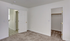 Bright bedroom with plush carpet, open closet, and a doorway leading to a sunlit hallway.