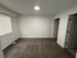 Bright and spacious room with clean carpet, fresh white walls, and ample natural light from a large window, featuring two doors for versatile access.