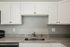 Modern kitchen with granite countertops, stainless steel sink, and white cabinetry.