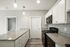 Modern kitchen with sleek granite countertops, white cabinetry, and stainless steel appliances.