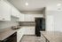 Contemporary kitchen with granite countertops, white cabinetry, and black appliances.
