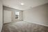 Bright, empty room with plush carpeting, a window, and modern lighting fixture.