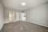 Modern bedroom with plush carpet, adjoining bathroom entrance, and open closet doors leading to the kitchen.