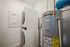 Compact laundry room featuring a stacked washer and dryer next to an energy-efficient water heater.
