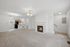 Bright and airy living room with cozy fireplace, plush carpet, and modern lighting, seamlessly connecting to an open kitchen with elegant cabinetry.