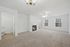 Bright and spacious living room with plush carpeting, featuring a cozy fireplace, elegant chandelier, and large windows for natural light.