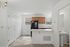 Bright kitchen with modern appliances, white countertops, and wooden cabinets, adjacent to a cozy dining area and a convenient bathroom.