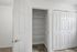Modern pantry with spacious white shelving and sleek closet doors, enhancing storage in a contemporary apartment.