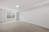 Bright, spacious room featuring plush carpeting, large window, and elegant white walls, ideal for a cozy living space or bedroom.