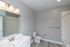 Modern bathroom with elegant fixtures, sleek vanity, and spacious mirror, complemented by stylish gray walls and flooring.